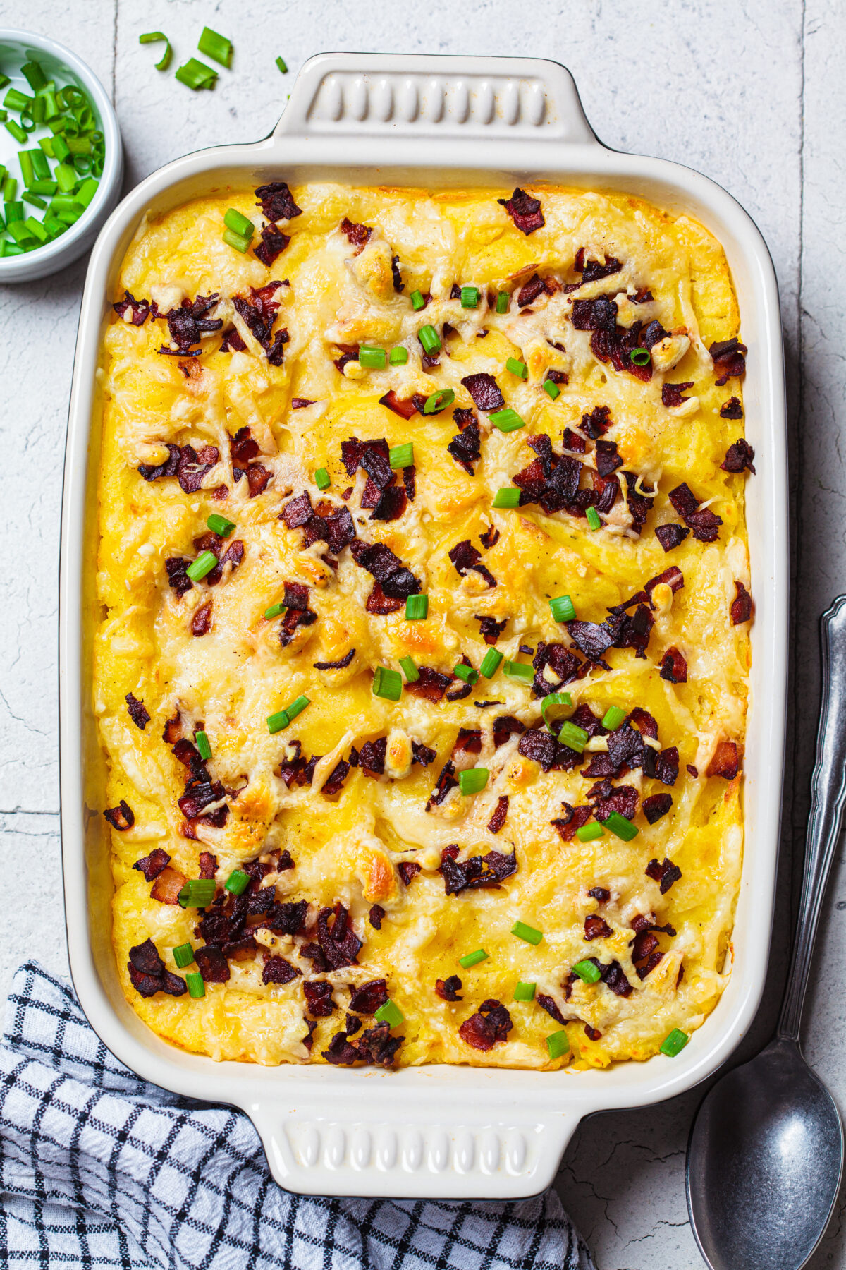 twice baked potato casserole in a dish with bacon and green onions