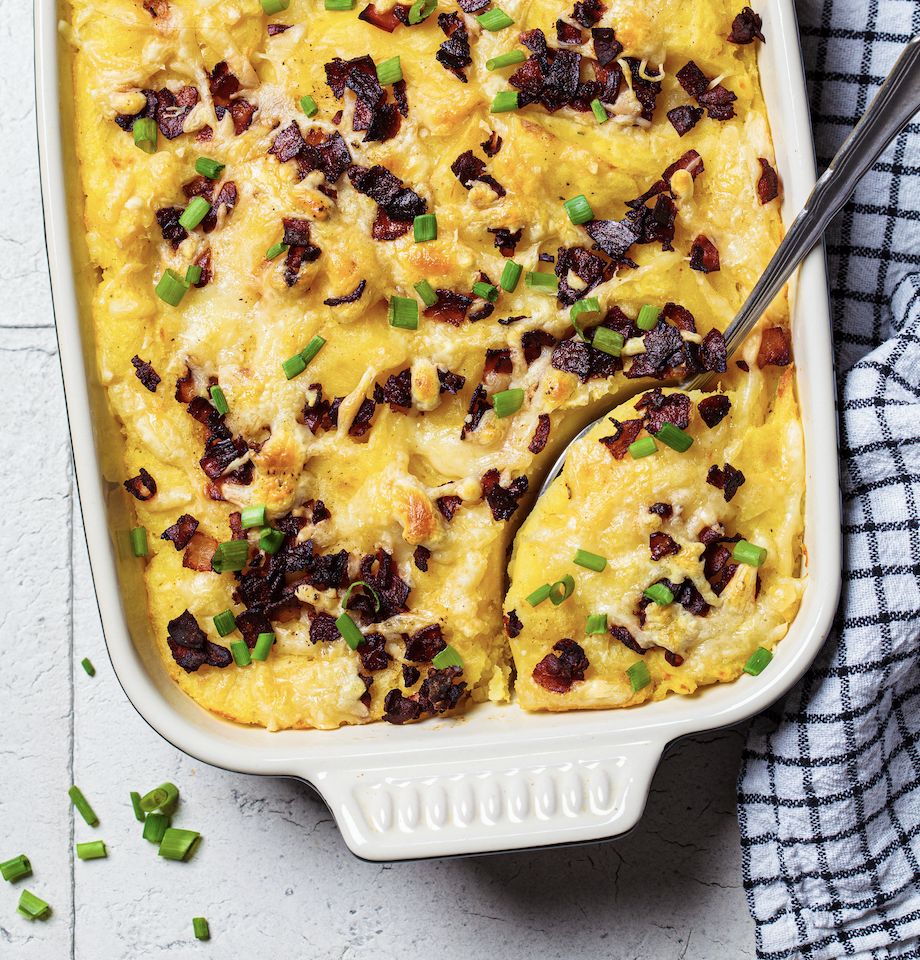 twice baked potato casserole with bacon and green onions with a serving spoon and a plaid linen