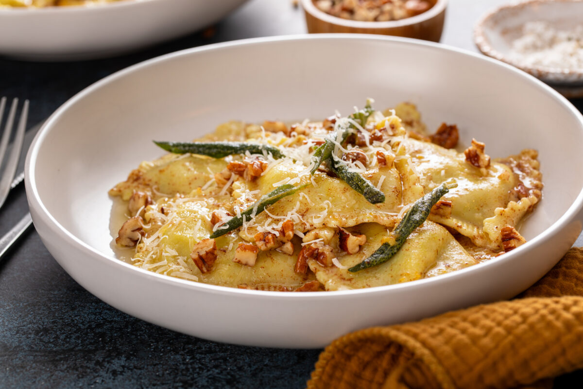 pumpkin ravioli with brown butter sauce, pecans, and crispy sage in a serving bowl