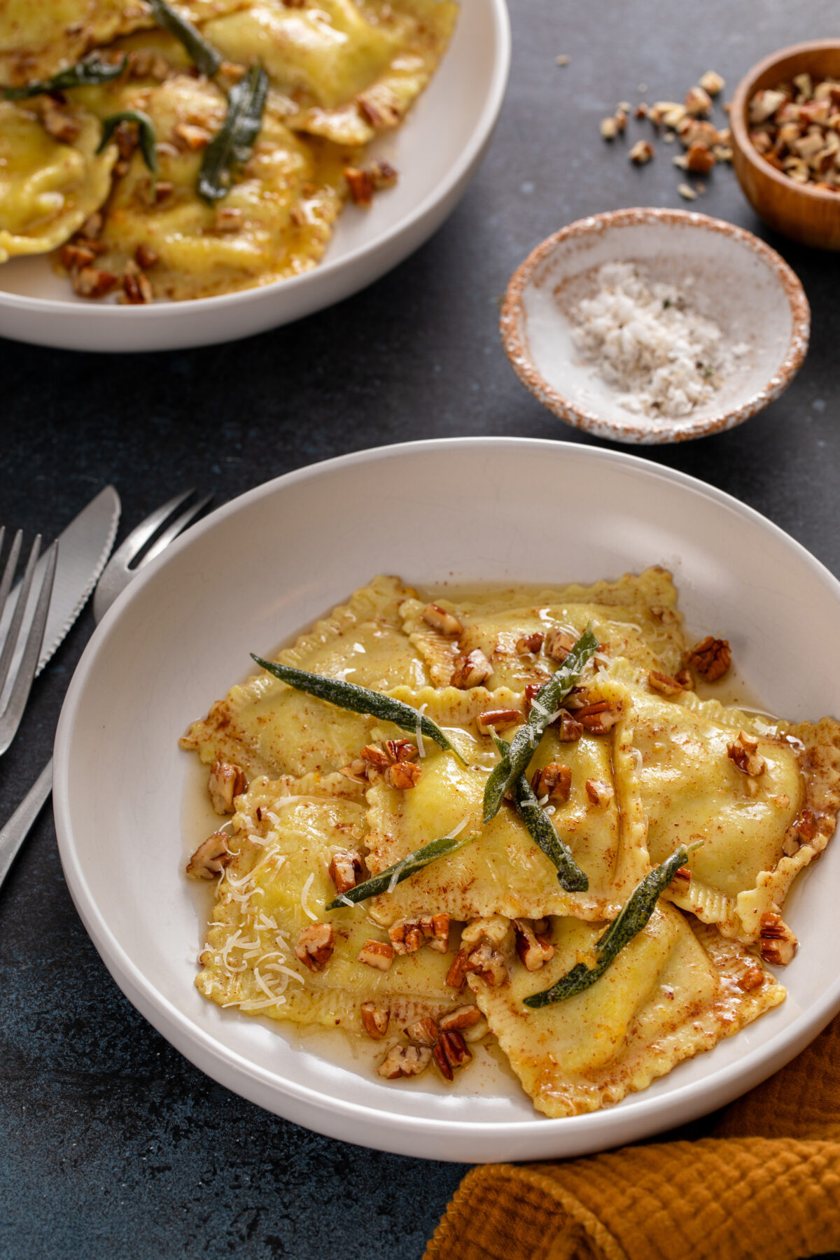 pumpkin ravioli with browned butter sauce, pecans and sage on a serving plate
